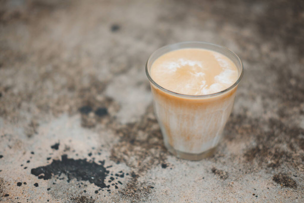 Primer plano del café Dirty Latte con textura sucia en la mesa de café.Eso se sirve muy claramente separado entre la leche helada y el café expreso en un vaso transparente. - Foto, Imagen