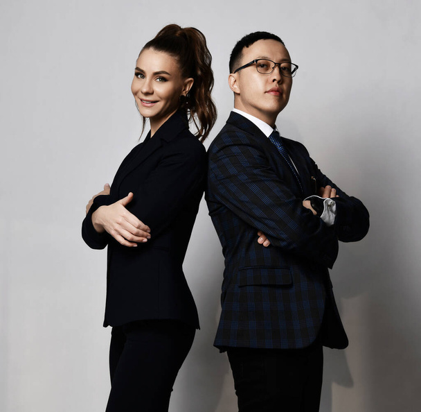 Positive man and woman business partners coworkers in official suits standing back to back with arms crossed at chest - Zdjęcie, obraz