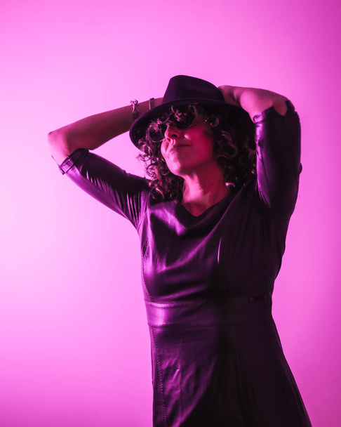 Studio lifestyle, a pretty young Caucasian woman in a session with elegant clothes and sunglasses, with neon pink light - Photo, image