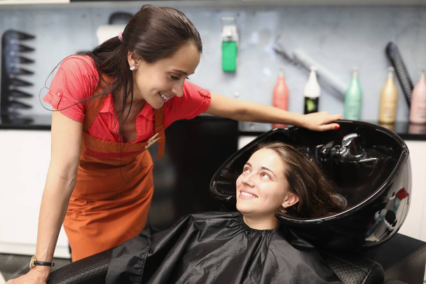 Kuaför müşteriye saçını nasıl yıkayacağını söyler. - Fotoğraf, Görsel