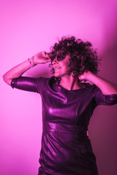 Studio lifestyle, a young Caucasian woman smiling in a session with elegant clothes and sunglasses, with neon pink light - Fotografie, Obrázek