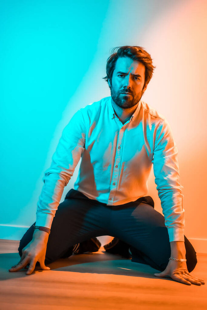 Studio lifestyle, sweet look of a Caucasian man in a white shirt, illuminated with an orange and blue neon light - Foto, Imagem