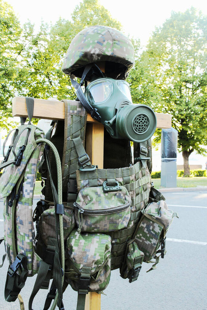uniforme militar con una máscara de gas y casco en una cruz de madera, símbolo de la muerte durante la guerra - Foto, Imagen