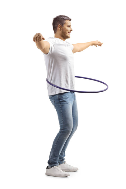 Young man in jeans and white t-shirt spinning a hula hoop isolated on white background - Photo, Image