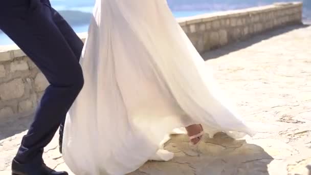 A vőlegény átöleli a menyasszonyt a karjaiban, a ruhája rebbenve tárja szét a lábait. - Felvétel, videó