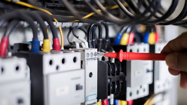 Elektriker-Ingenieur-Arbeitsprüfer misst Spannung und Strom der Stromleitung in der Schaltschranksteuerung. - Foto, Bild