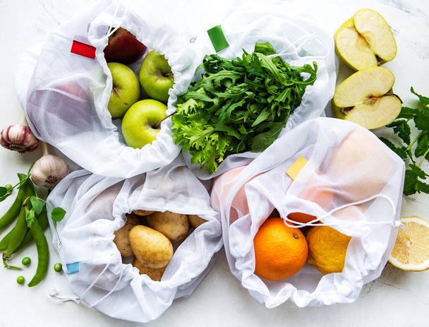 Frutta e verdura estiva in sacchetti di rete eco-friendly riutilizzabili su fondo marmo. Zero rifiuti di shopping. Concetto ecologico. - Foto, immagini
