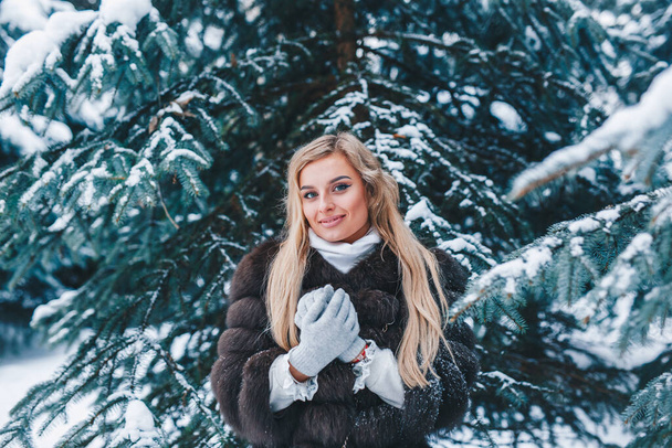 Young beautiful woman in winter clothes in forest - Valokuva, kuva