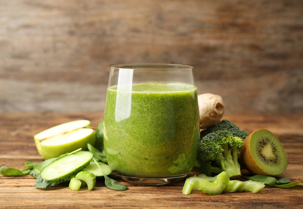 Green juice and fresh ingredients on wooden table - Valokuva, kuva