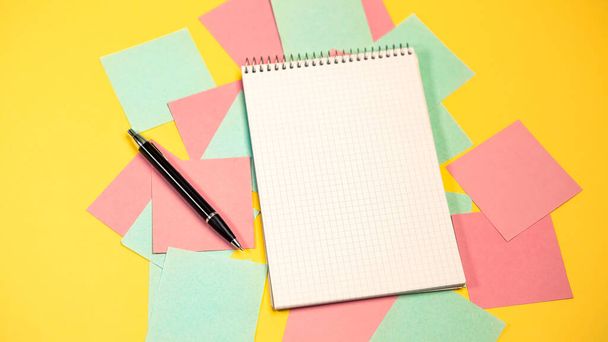 トップ表示カラフルなメモ粘着ピンクリップ空のノート散乱混沌とした方法。黒いペンで紙の空白のメモ帳は黄色の背景を隔離しました。ビジネス、教育、仕事の概念。平敷 - 写真・画像