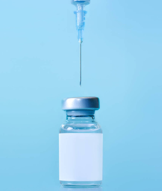 Vaccine in a bottle with a syringe on a blue background.The concept of medicine, healthcare and science.Coronavirus vaccine.Copy space for text. - Photo, image