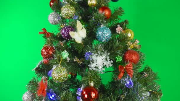 Ein Weihnachtsbaum dreht sich auf blauem Hintergrund, geschmückt mit einem blinkenden Gerland und bunten Spielzeugen - Filmmaterial, Video