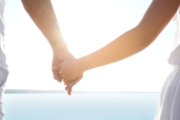 Couple holding hands together near river, closeup. Nature healing power - Foto, Imagem