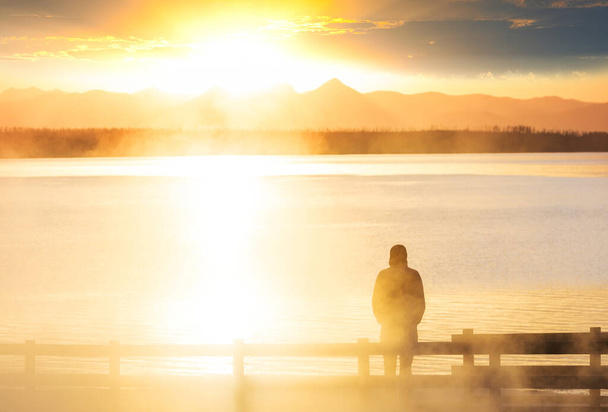 Un hombre descansa a gusto junto al lago tranquilo. Vacaciones de relajación - Foto, imagen