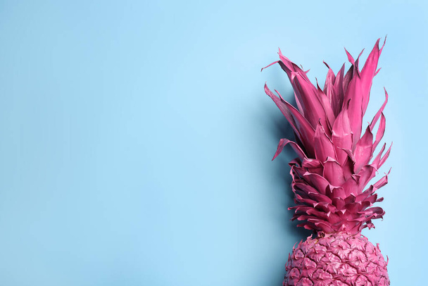 Top view of painted pink pineapple on light blue background, space for text. Creative concept - Foto, imagen