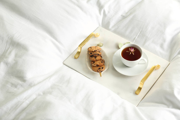 Cup of aromatic tea and cookies on soft blanket. Space for text - 写真・画像