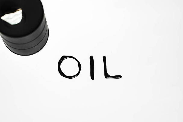 Oil industry concept. Spilled oil from a mini barrel on white background - Photo, image
