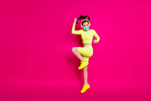 Full length body size side profile photo of sportswoman jumping exercising listening to music isolated on vivid fuchsia color background - Fotó, kép
