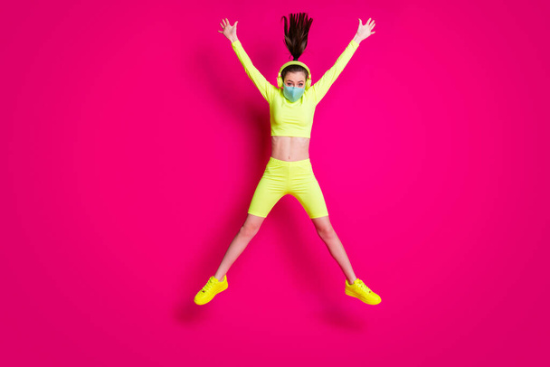 Full length body size photo of girl jumping like star wearing headphones yellow sportswear isolated on bright fuchsia color background - Photo, Image