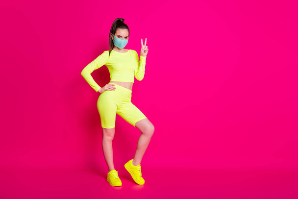 Full length body size photo of girl wearing sportswear sneakers showing v-sign gesture isolated on bright fuchsia color background - Zdjęcie, obraz