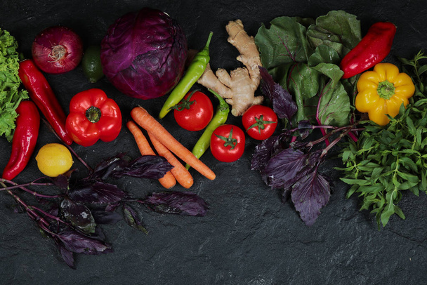 Pimentos, tomates, verduras, cenoura e gengibre sobre fundo escuro - Foto, Imagem