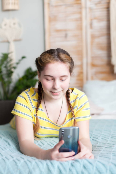 Pre-teen dziewczyna smsy na smartfonie i leżąc w łóżku w hom - Zdjęcie, obraz