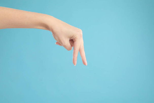 Woman imitating walk with hand on light blue background, closeup. Finger gesture - Photo, Image