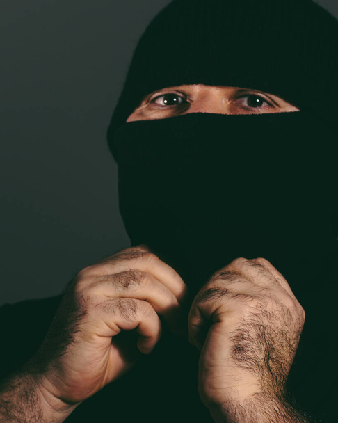 A vertical shot of a male hiding his face with a black mask - Fotoğraf, Görsel