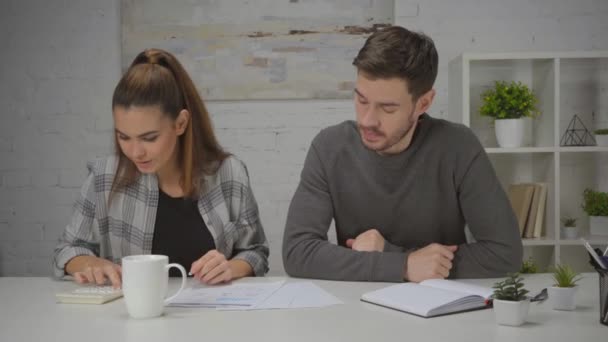 homem descontente jogando caneta na mesa e mulher feliz usando calculadora em casa - Filmagem, Vídeo