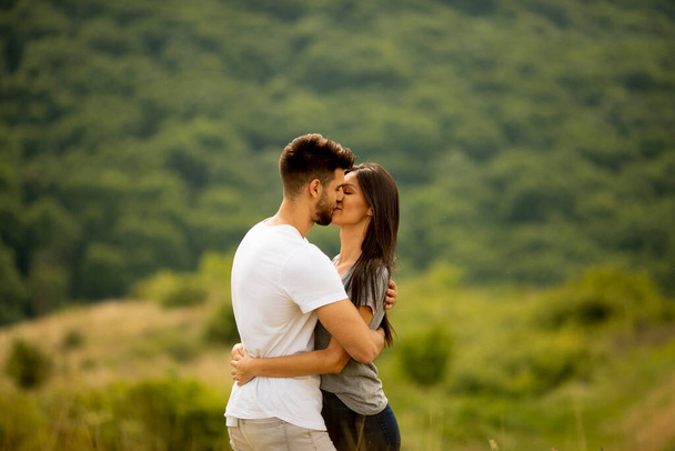 Feliz joven pareja enamorada en el campo de hierba en un día de verano - Foto, Imagen