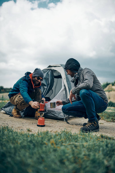 Two campers crouching by the tent and preparing coffee. - Photo, Image