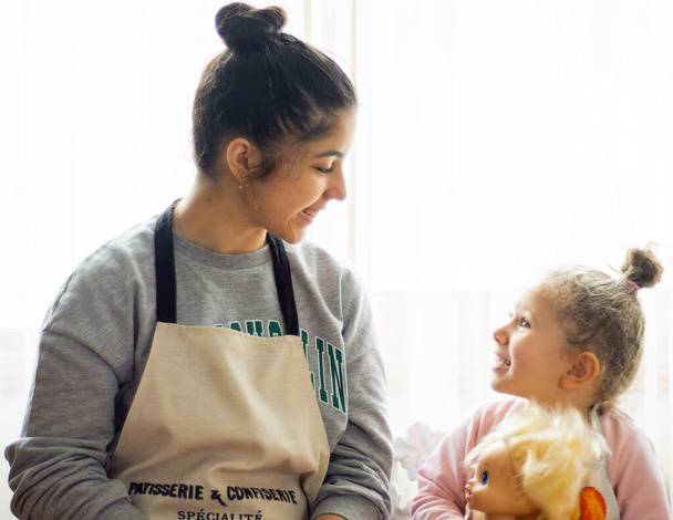 台所で女の子。幸せな家族面白い子供たちは生地を準備し、キッチンでクッキーを焼き、お互いに選択的な焦点の手を見て. - 写真・画像