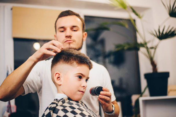 Hairdresser barbershop and small boy sitting on a chair - Fotoğraf, Görsel