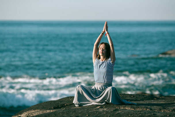 Dziewczyna medytująca na wybrzeżu oceanu. Joga i sprawność. - Zdjęcie, obraz