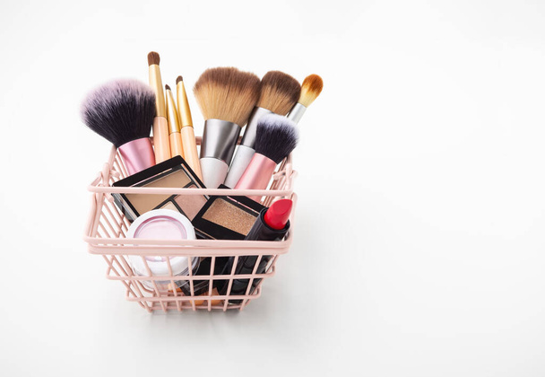 Maquillaje productos cosméticos en cesta de la compra sobre fondo blanco - Foto, Imagen