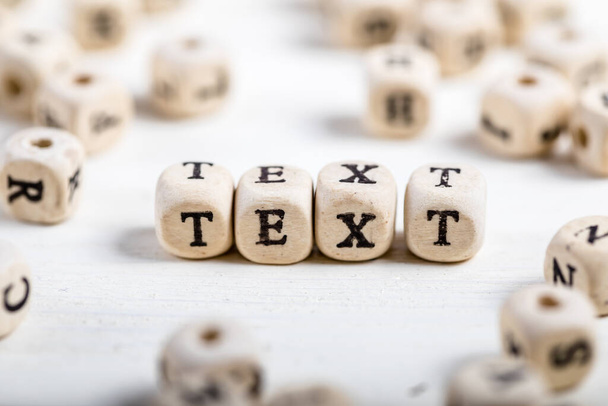 Слово TEXT образовано деревянными алфавитными блоками. Старый деревянный стол. - Фото, изображение