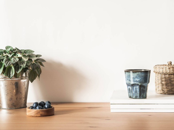 Koti asetelma eri tyylistä koriste-esineitä puupöydällä vastaan valkoinen seinä. Etunäkymä. Kopioi tila - Valokuva, kuva