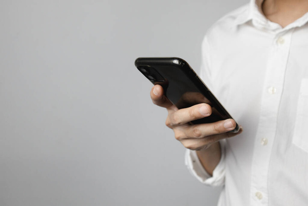 Hombre con camisa blanca sosteniendo el teléfono inteligente, Concéntrate en el teléfono inteligente, Espacio para copiar. - Foto, Imagen