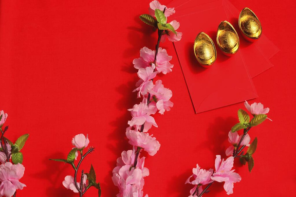Capodanno cinese Primavera festival decorazioni rosso pacchetto e lingotti d'oro su sfondo rosso con fiori di prugna fiore. Traduzione cinese: buona fortuna, buona fortuna, ricchezza e flusso di denaro.  - Foto, immagini