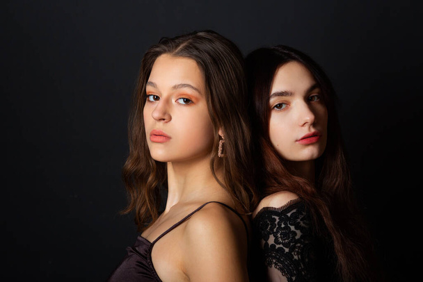 two beautiful young women with makeup and hairstyle on a black background  - Fotoğraf, Görsel