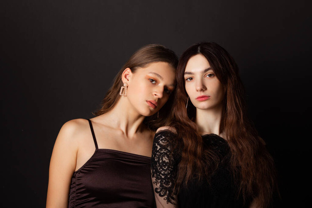 two beautiful young women with makeup and hairstyle on a black background  - 写真・画像