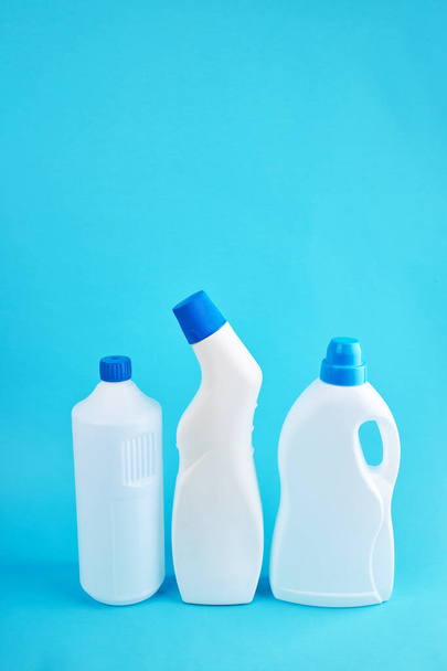 garrafas de produtos químicos em branco sobre fundo azul. orientação vertical. conceito de serviço de limpeza - Foto, Imagem