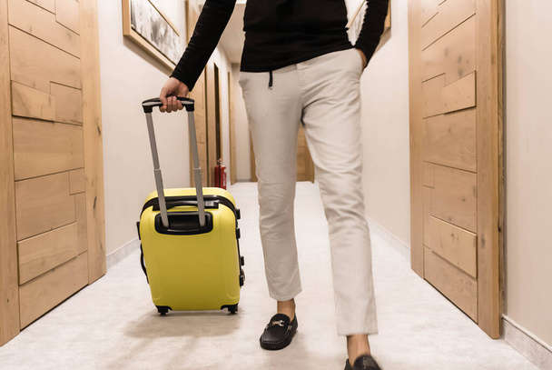 Hombre irreconocible con maleta amarilla caminando por el vestíbulo. - Foto, Imagen