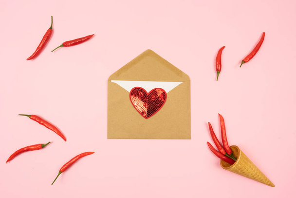 Red hot chilli peppers with a brown envelope with a red lie on a pink background table. Copy space. - Fotoğraf, Görsel