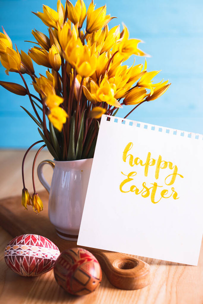 happy easter card. still life - beautiful Easter egg Pysanka handmade and bouquet of wild tulips with inscription happy easte - Фото, изображение
