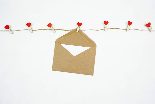 A  brown envelope with a blank letter hangs on the string with red hearted pins - Fotoğraf, Görsel