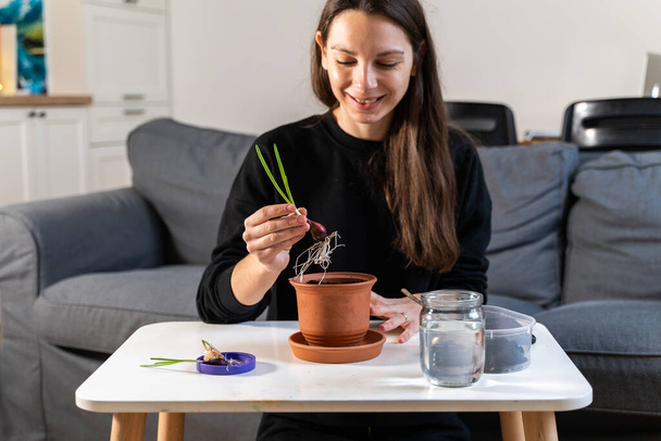 Young millennial woman planting onion herbs at home in a pot. Home gardening hobby. Zero waste sustainable lifestyle. Healthy clean food - Foto, Bild