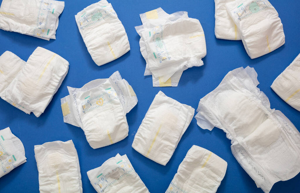 Colección de pañales para bebés sobre fondo de color azul. Pañales recién nacidos abiertos y cerrados planas, vista superior - Foto, Imagen
