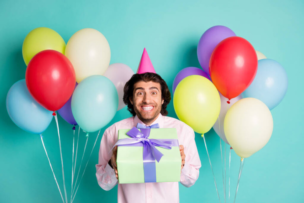 Portrait of magnificent guy deliver present box colorful helium balloons wear formal cone cap isolated on turquoise color background - Φωτογραφία, εικόνα