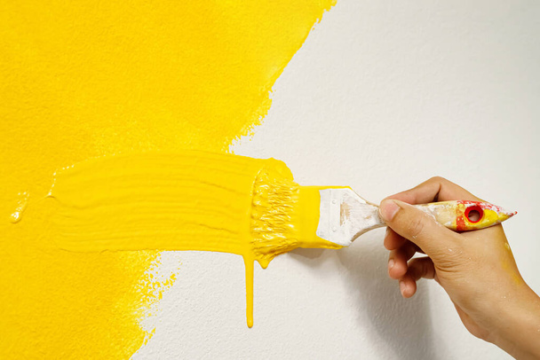 El pintor está pintando las paredes en amarillo con el interior de la sala de estar de la casa. - Foto, imagen